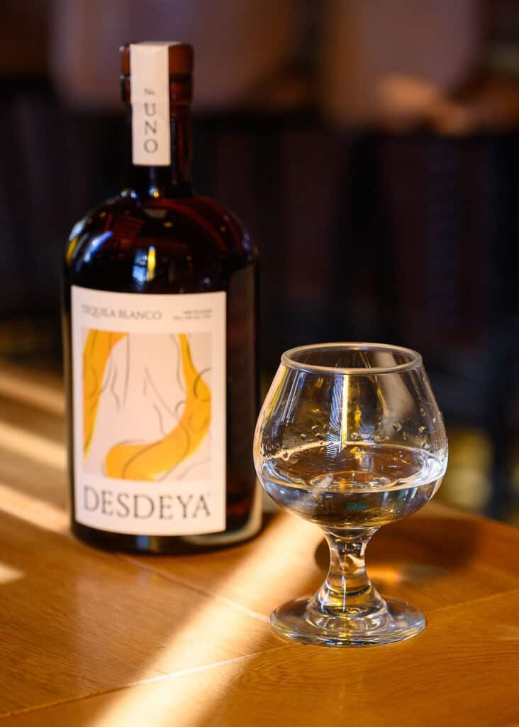 A bottle of Desdeya tequila next to a glass