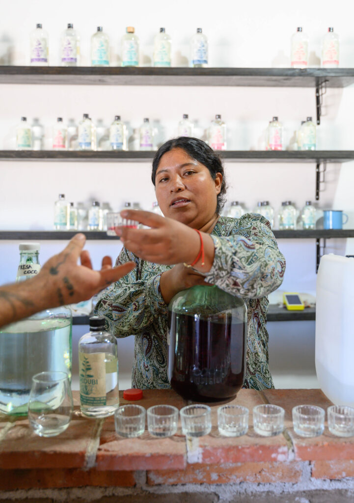 A woman serves mezcal in a veladora mezcal glass