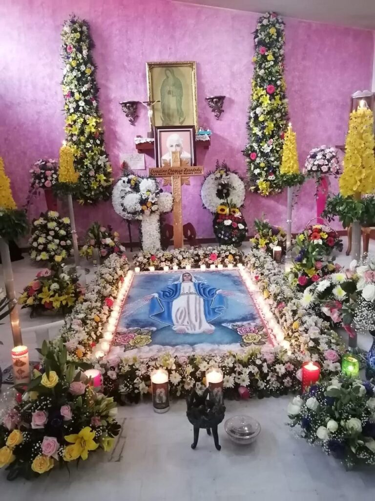 A picture of an altar in Mexico, with veladoras (votives) and flowers