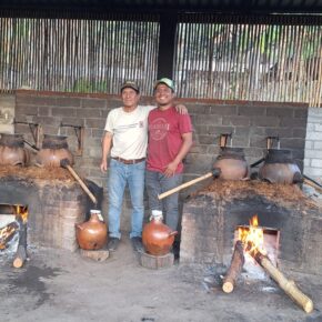 Two men stand in a palenque where ancestral mezcal is made